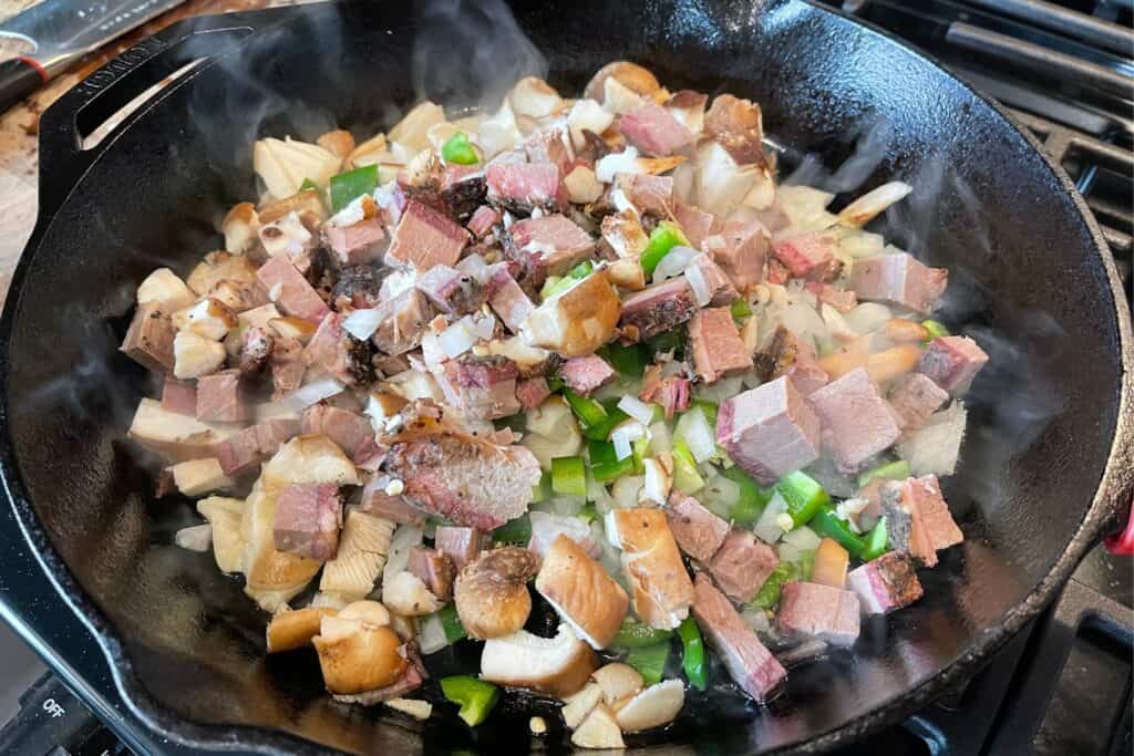 onion, mushroom, jalapeño, and leftover brisket in a large cast iron skillet