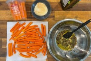 dried carrot sticks on a paper towel and olive oil mixed with red pepper flakes, parsley flakes, and black pepper