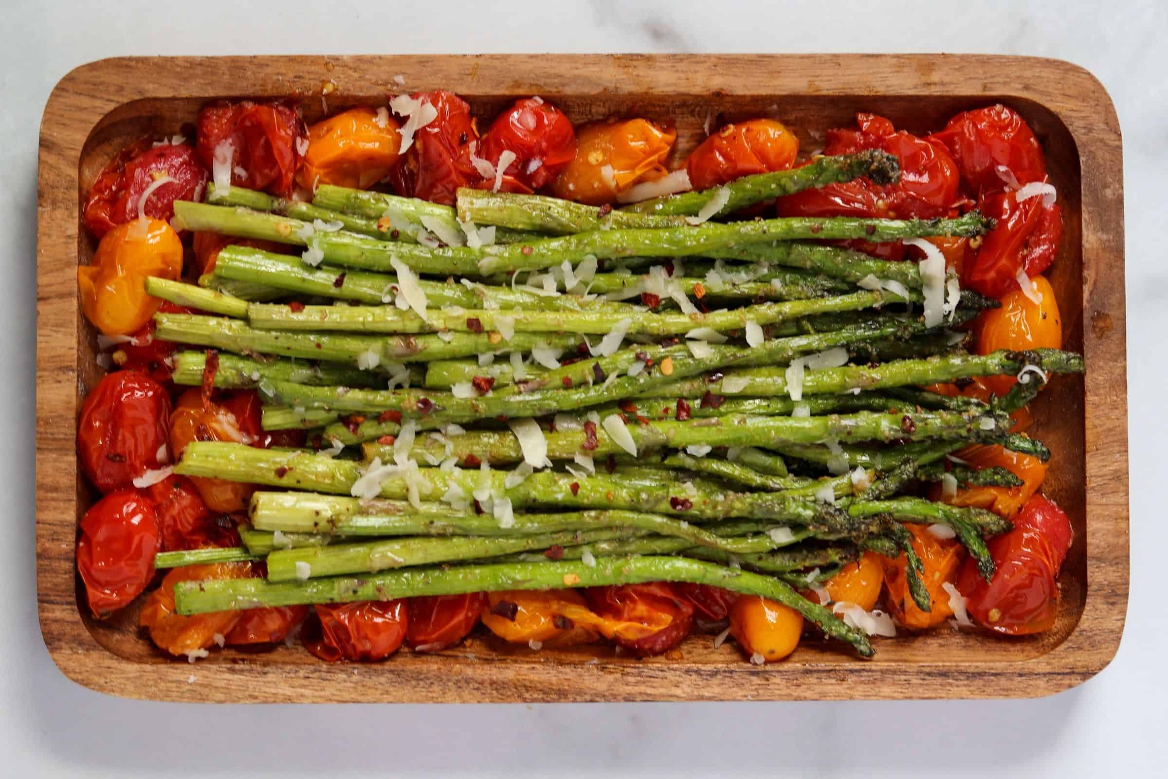 asparagus and tomatoes on a brown plate with grated parmesan