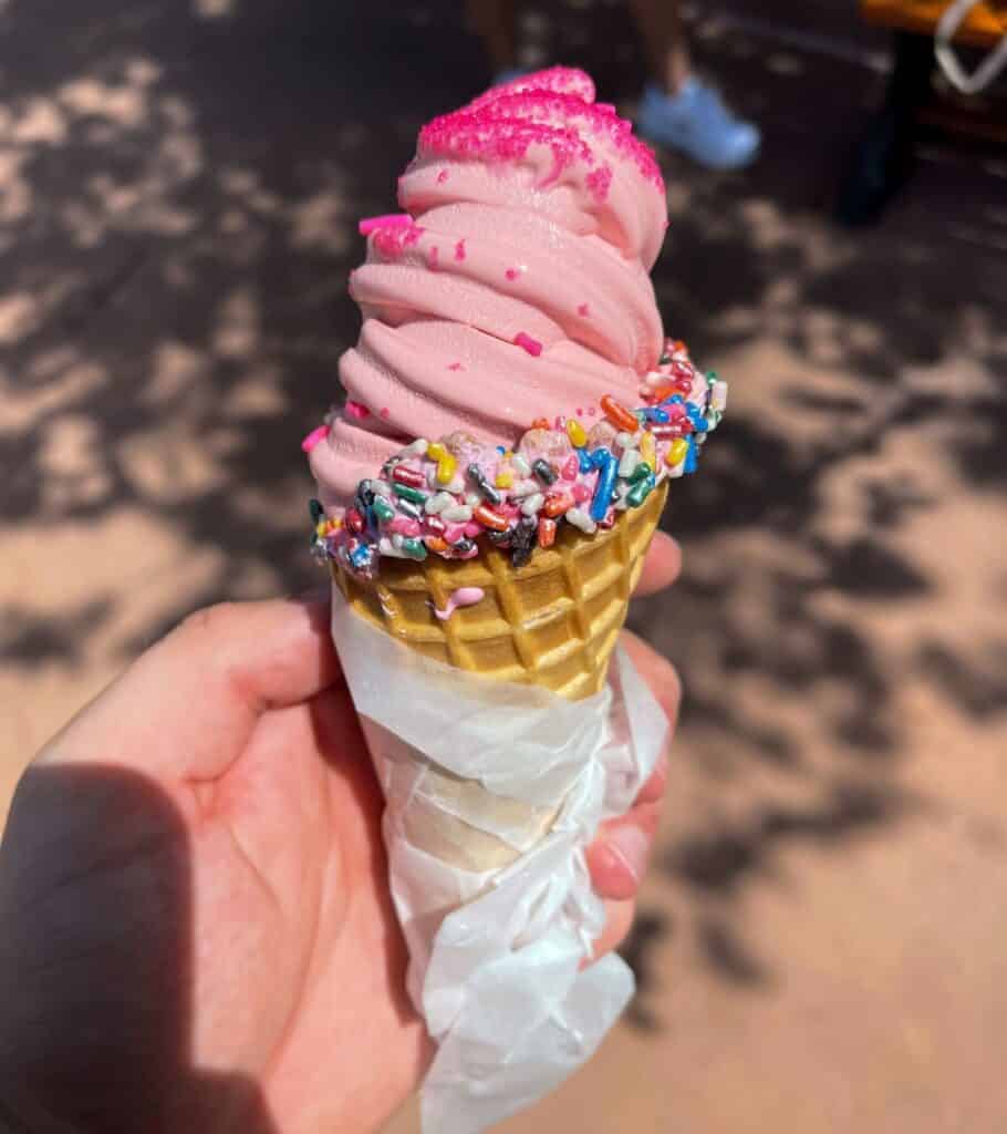 strawberry soft serve in a waffle cone