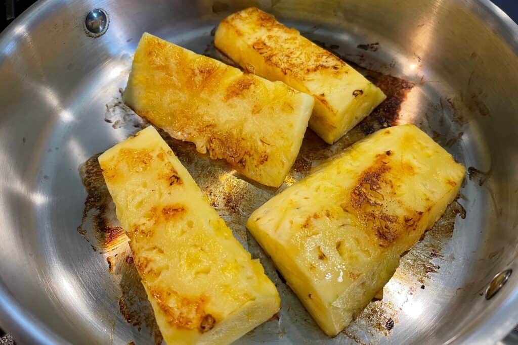 toasting pineapple slices in a pan
