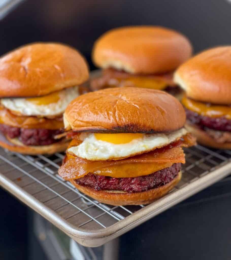 four smoked burgers on a rack beside the Traeger grill
