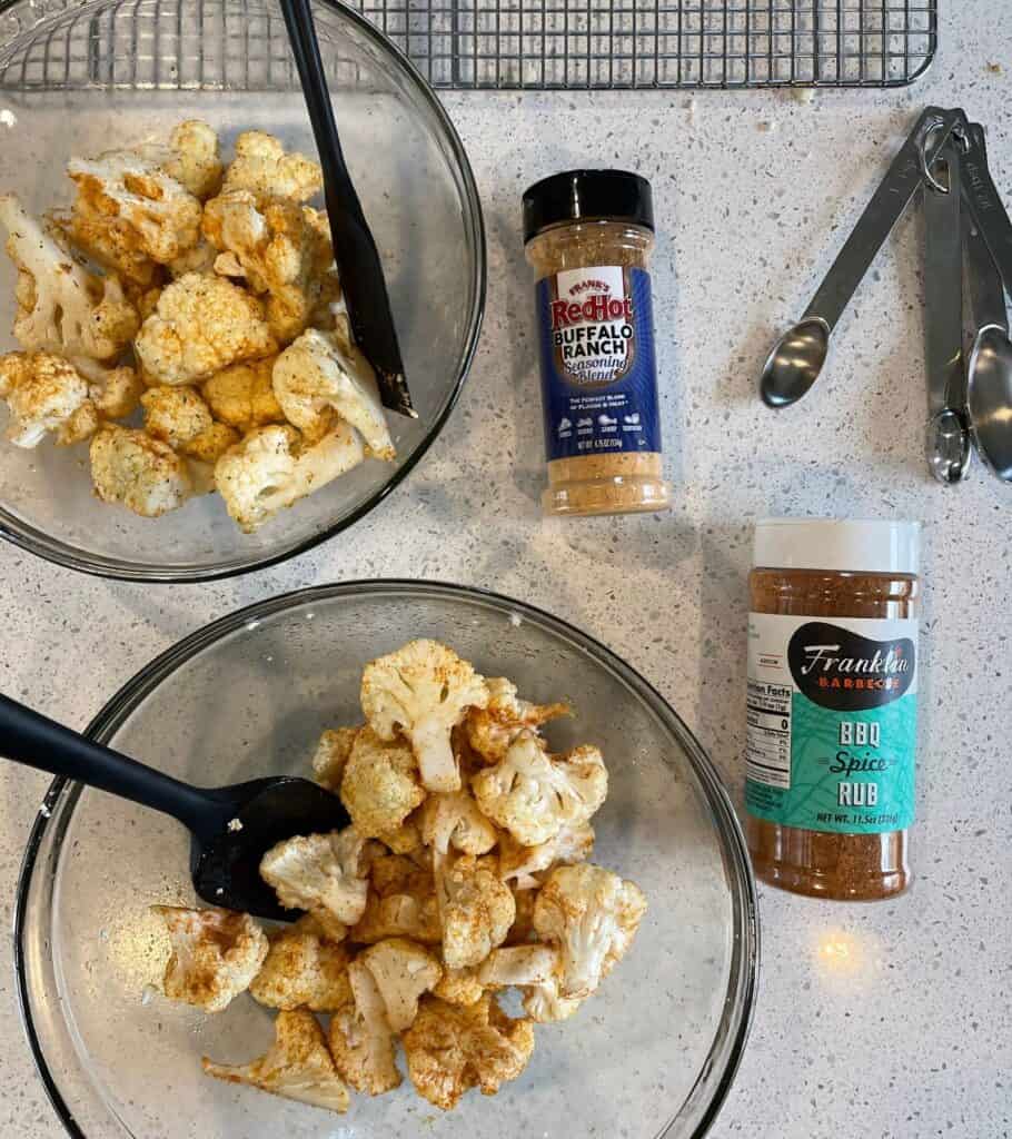 cauliflower florets tossed in olive oil and seasoning rubs in mixing bowls
