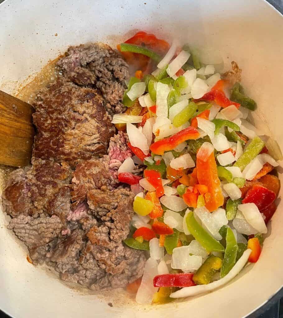 browned ground beef in a pot with frozen fajita vegetables