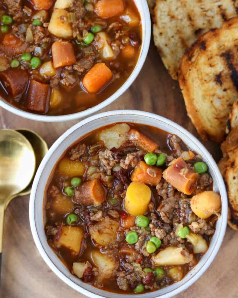two bowls of ground beef vegetable soup with grilled bread