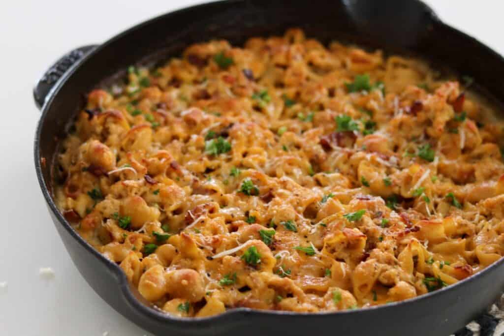 chicken bacon ranch mac and cheese in a cast iron skillet with parsley and grated parmesan
