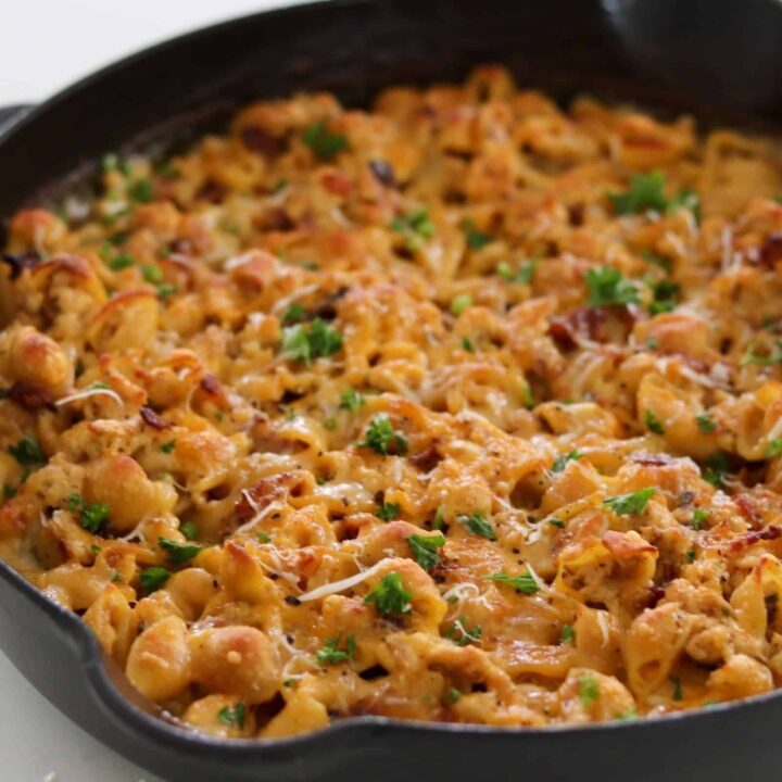 chicken bacon ranch mac and cheese in a cast iron skillet with parsley and grated parmesan