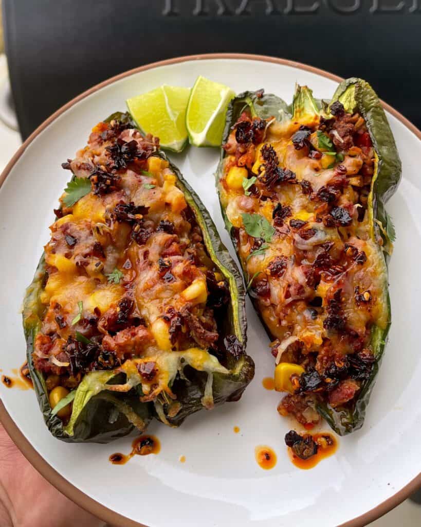 two stuffed peppers on a plate with lime wedges