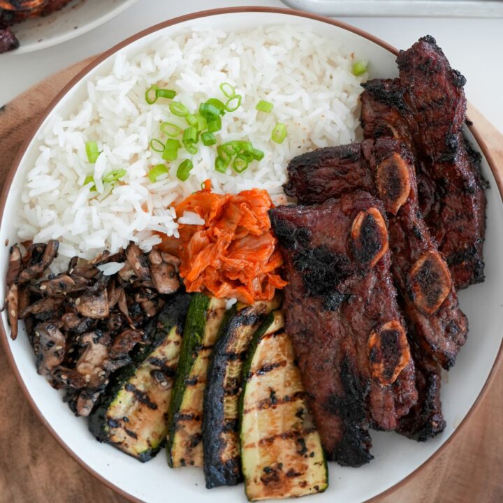 grilled flanken short ribs with grilled zucchini and mushrooms in a bowl with rice and kimchi