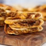 ground beef quesadillas stacked on a cutting board