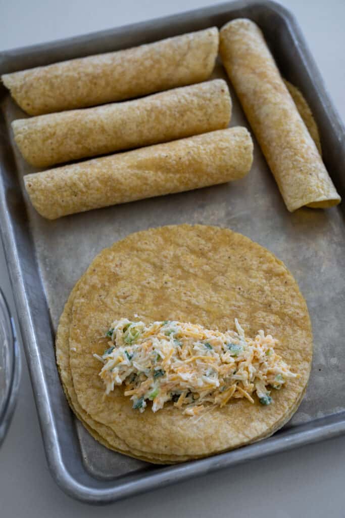 cheese rolled tortillas on a sheet pan