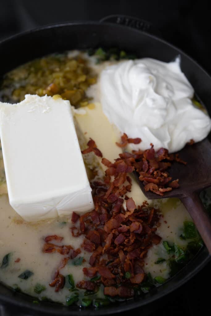 queso blanco, butter, sour cream, cooked bacon, and diced green chiles in a cast iron skillet