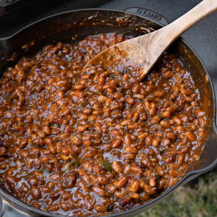 wooden spoon in a skillet of smoked baked beans resting on a Traeger grill