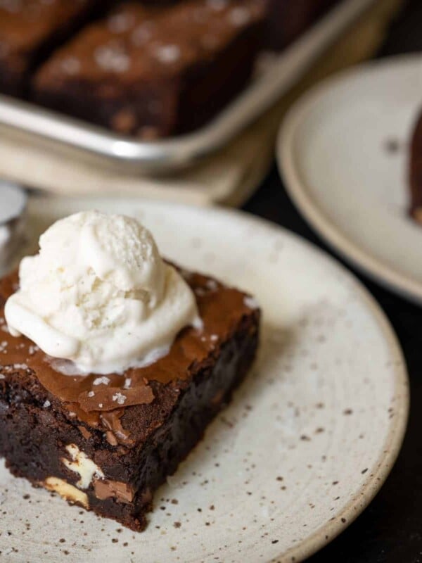 Two slices of brownies with ice cream on top.