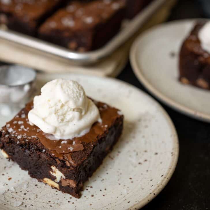 Two slices of brownies with ice cream on top.