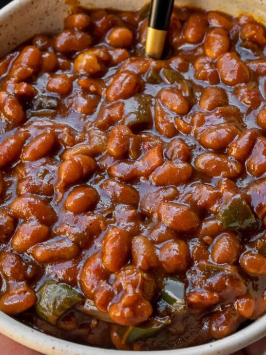 holding a bowl of smoked baked beans in front of a Traeger grill