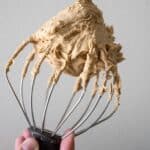 A whisk attachment from the stand mixer with espresso buttercream on it.