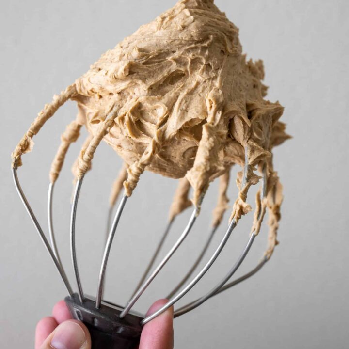 A whisk attachment from the stand mixer with espresso buttercream on it.