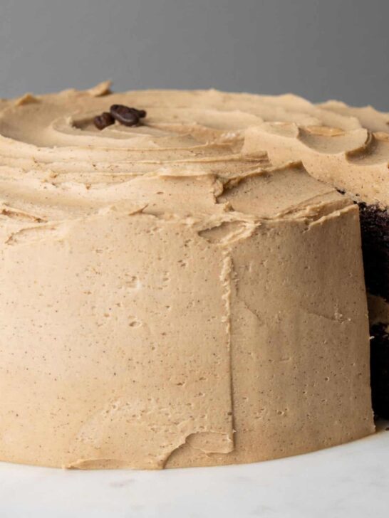 A chocolate cake frosted with espresso buttercream with one slice slightly pulled out.
