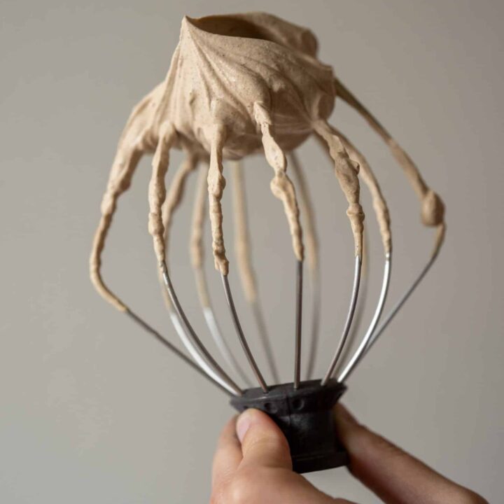 The whisk attachment from a stand mixer with espresso whipped cream on it.