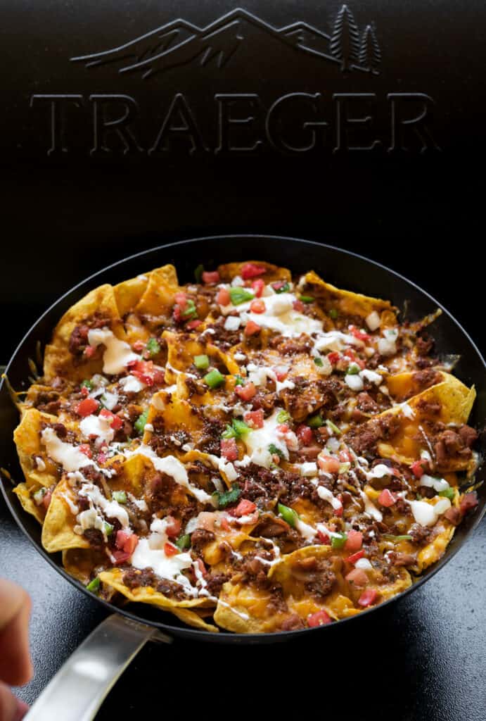 holding a carbon steel skillet with Traeger smoked nachos