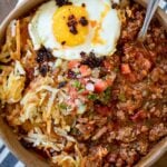 breakfast chili in a bowl with a fried egg, hash browns, and pico de gallo