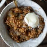 cinnamon apple crisp in a bowl with a dollop of vanilla ice cream