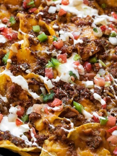 chili cheese nachos in a skillet in front of a Traeger grill