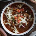 bowl of Mexican cauliflower rice soup topped with shredded pepper jack cheese and pico de gallo