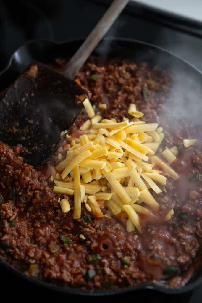 tamale pie filling in a skillet with cheddar cheese