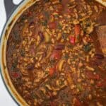 ground pork chili in a Dutch oven with a wooden spoon in it