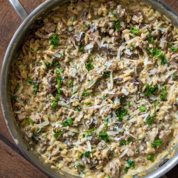 ground turkey and mushroom orzo in a stainless steel sauté pan garnished with parsley