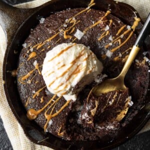 golden spoon in a cast iron skillet brownie with ice cream and a cookie butter drizzle