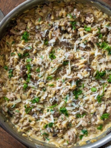 ground turkey and mushroom orzo in a stainless steel saut&eacute; pan garnished with parsley