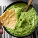 dipping a tortilla chip in a bowl of smoked guacamole salsa