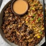 teriyaki ground bison and rice in a bowl with a small wooden bowl of yum yum sauce
