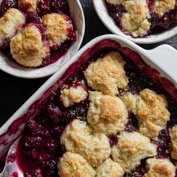two bowls with servings of smoked cobbler beside the full baking dish