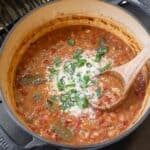 smoked borracho beans on a Traeger grill garnished with cotija cheese and cilantro