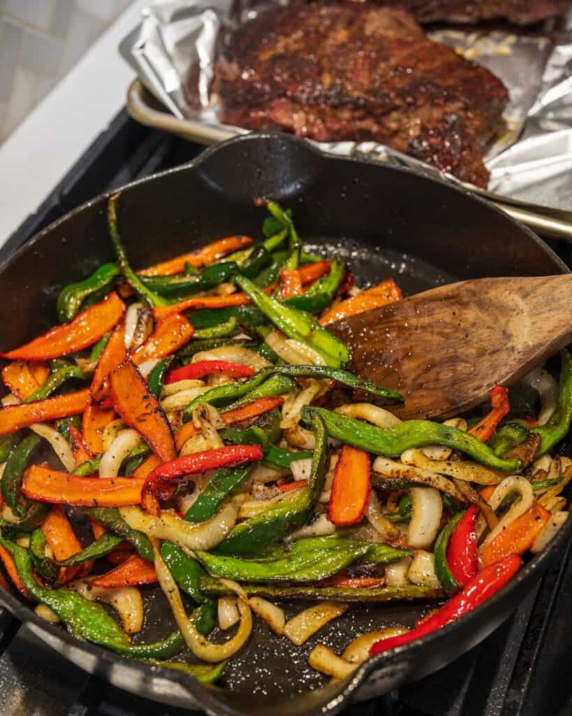 sautéing smoked peppers and onions in a cast iron skillet after searing a smoked steak in the skillet