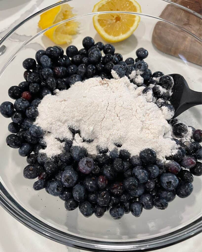 blueberries with sugar, corn starch, cinnamon, salt, lemon juice, and vanilla in a glass mixing bowl