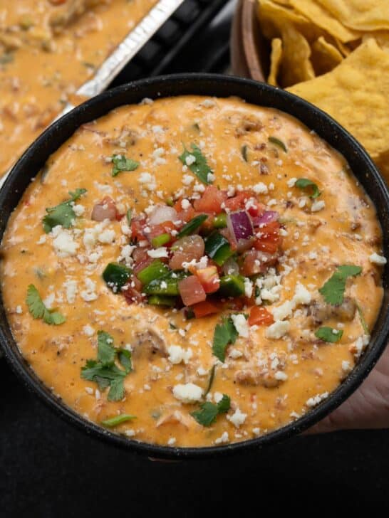 bowl of smoked queso with pico de gallo, cilantro, and cotija cheese