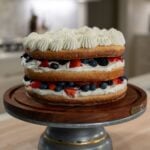 Three layer milk and berries cake with a sponge cake layer, a whipped cream layer, and a summer berries layer.