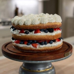Three layer milk and berries cake with a sponge cake layer, a whipped cream layer, and a summer berries layer.