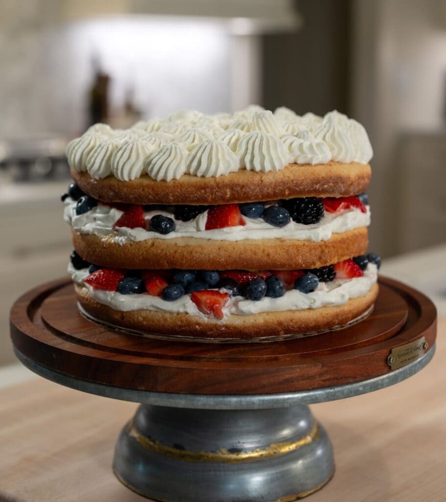 Three layer milk and berries cake with a sponge cake layer, a whipped cream layer, and a summer berries layer.