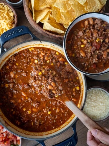 smoked taco soup in a Dutch oven surrounded by garnishes of tortilla chips, cornbread, pico de gallo, cotija cheese, shredded cheddar, and salsa macha